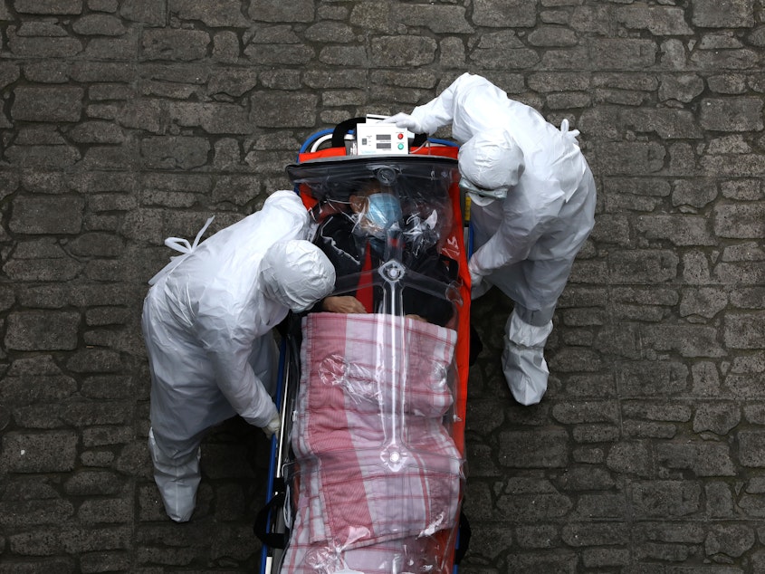 caption: Medical staff in protective gear move a patient with COVID-19 from an ambulance to a hospital in Seoul.