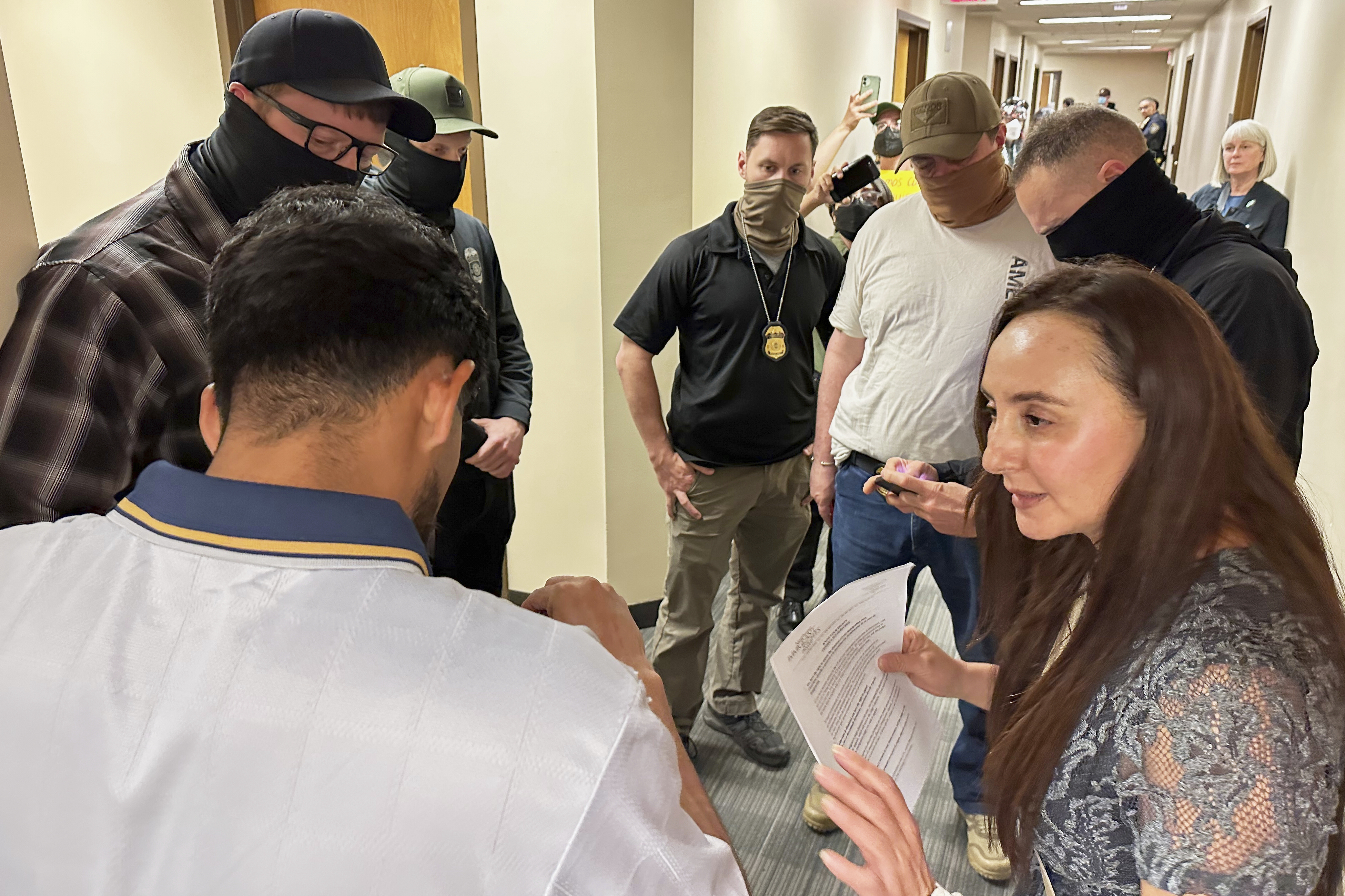 caption: Immigration court volunteer Marjorie Miller gives guidance and support to a Colombian man who was about to be taken into custody by Immigration and Custom Enforcement officers in the hallway after his hearing with an immigration judge in Seattle, June 3, 2025. 