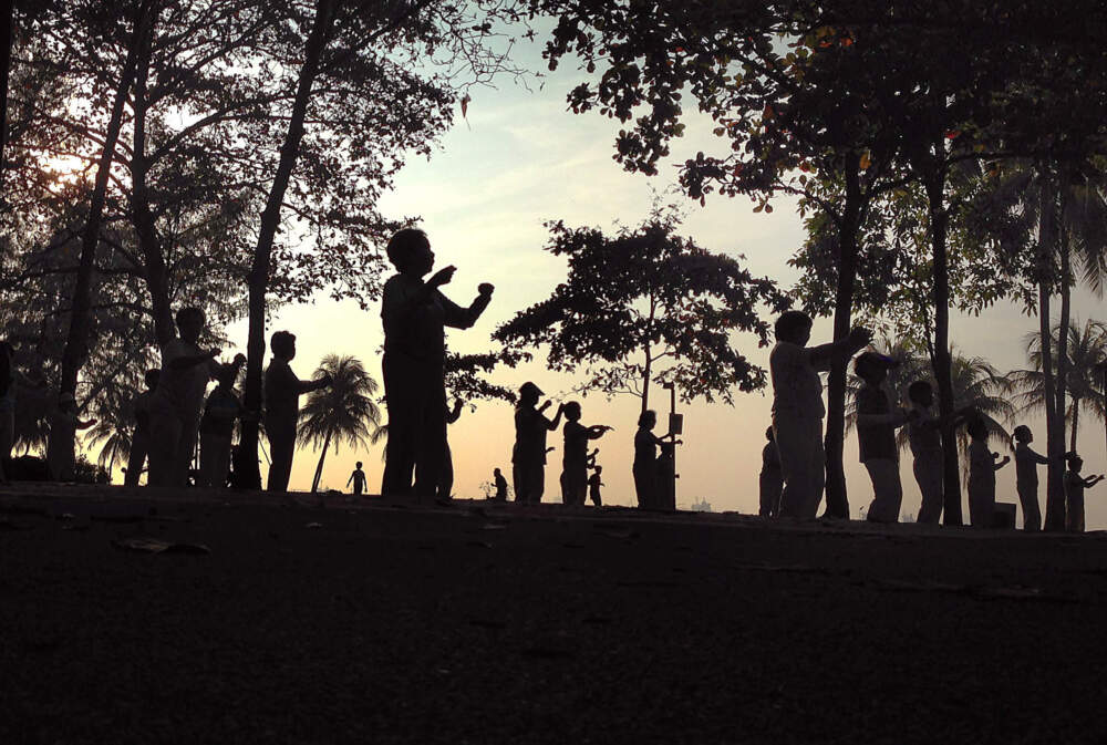 caption: Elderly people are silhouetted as they exercise early in the morning on Tuesday Oct. 29, 2013, by the beach, in Singapore. (Wong Maye-E/AP)