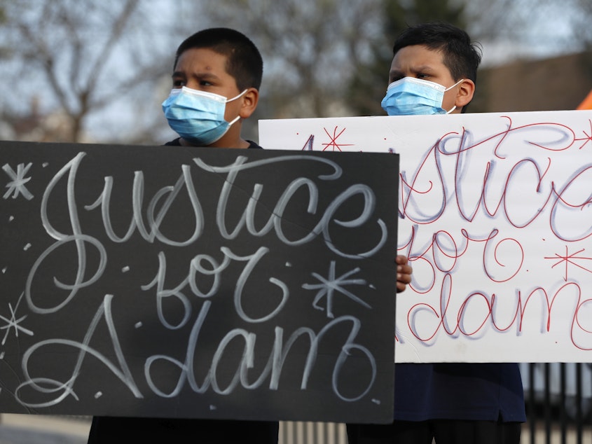 caption: Two boys hold signs at an April 6 news conference, days after a Chicago police officer fatally shot 13-year-old Adam Toledo.