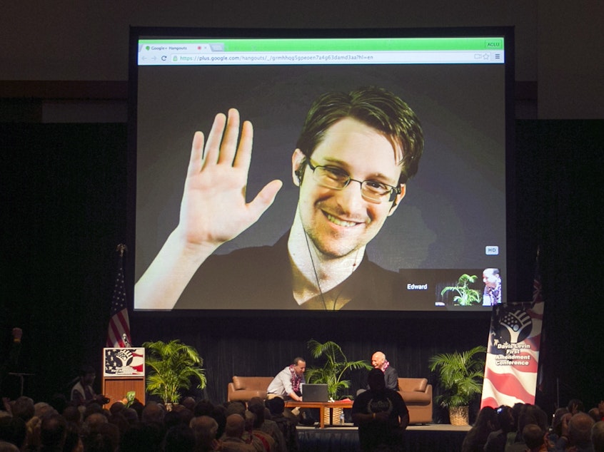 caption: Edward Snowden appears on a live video feed broadcast from Moscow at an event sponsored by the ACLU Hawaii in Honolulu on Feb. 14, 2015.