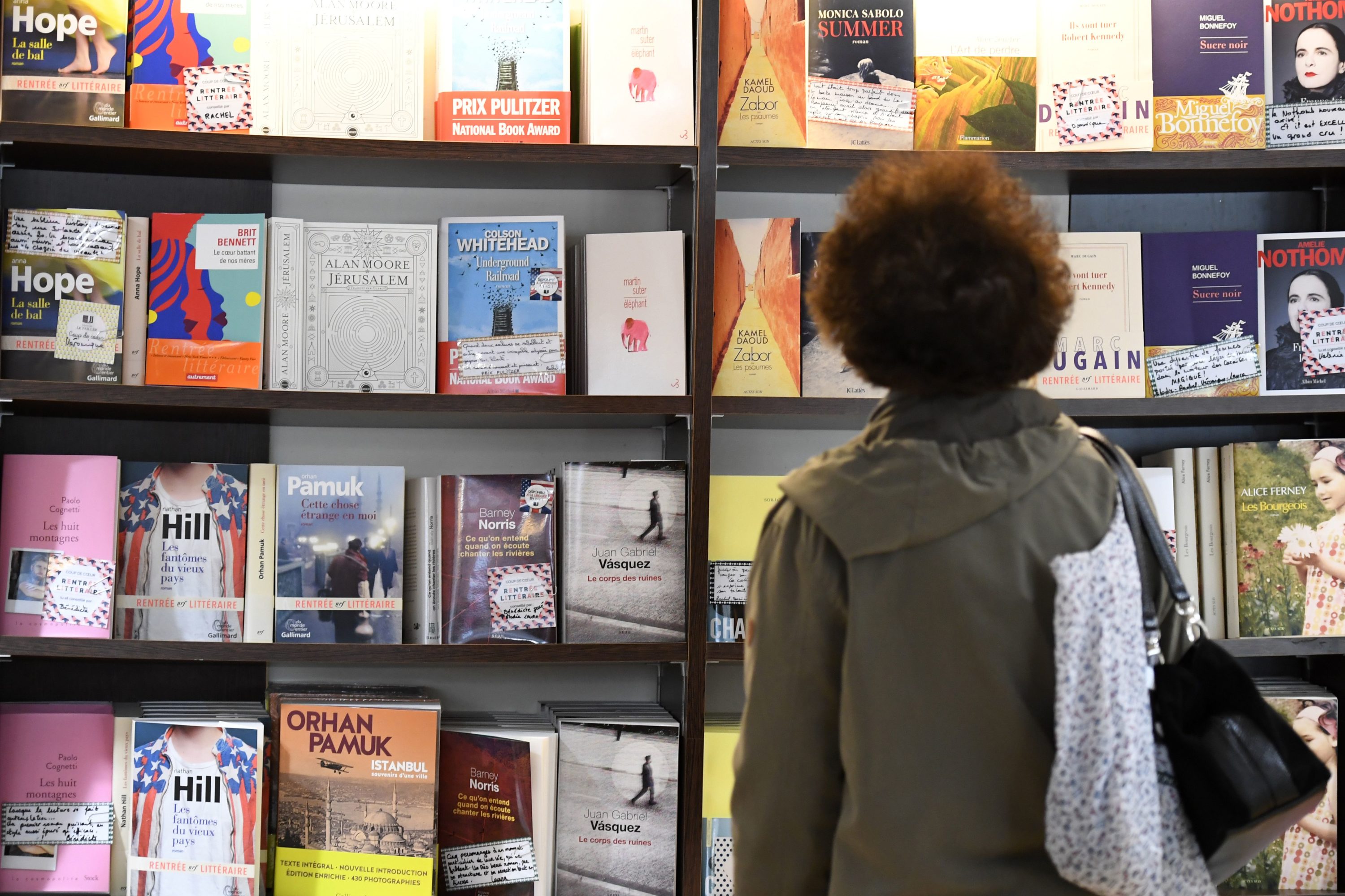 caption: A visitor looks at books in a book shop. (Damien Meyer/AFP via Getty Images)