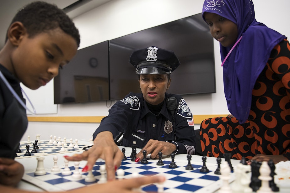 caption: From left, Kirubel Daniel, 8, Detective Denise "Cookie" Bouldin and Deeqo Abdullahi, 11, play a game of chess on Tuesday, November 28, 2017, at the Rainier Beach Library in Seattle. 