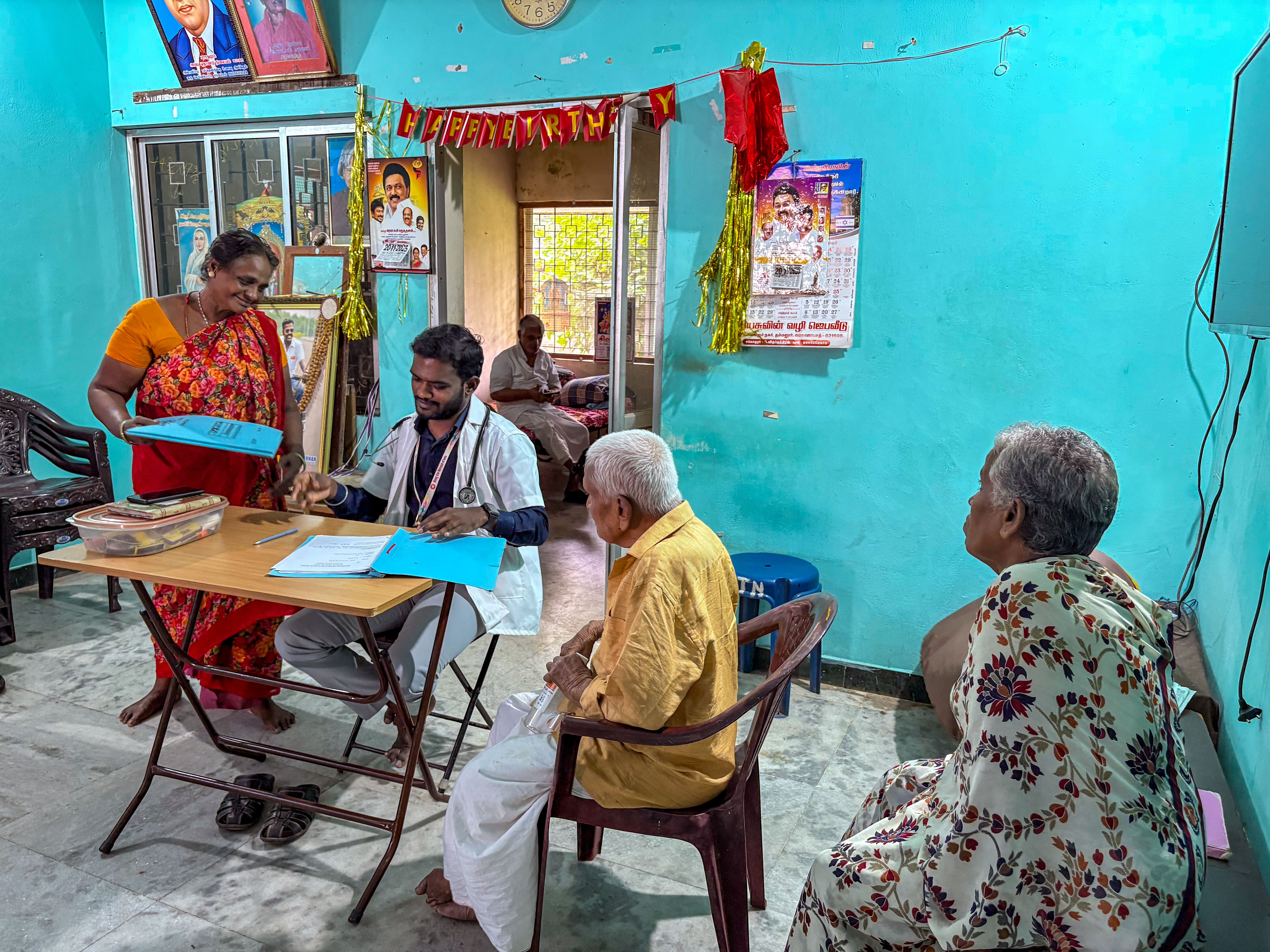 caption: A doctor visits residents of the Bharathapuram leprosy colony. Even though they are cured of the disease, they have long-term effects — crippled hands, blindness, amputations and, most of all, foot lesions that, if untreated, can become infected.