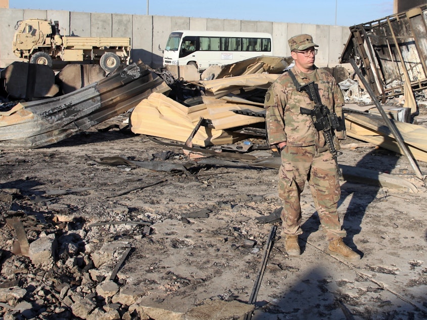 caption: A U.S. soldier stands at a spot struck by a barrage of Iranian missiles at Ain al-Asad air base, in Anbar, Iraq, in January. The attack was in retaliation for the U.S. drone strike that killed Iranian Gen. Qassem Soleimani. The U.S. is drawing down 3,000 troops in Iraq and Afghanistan.