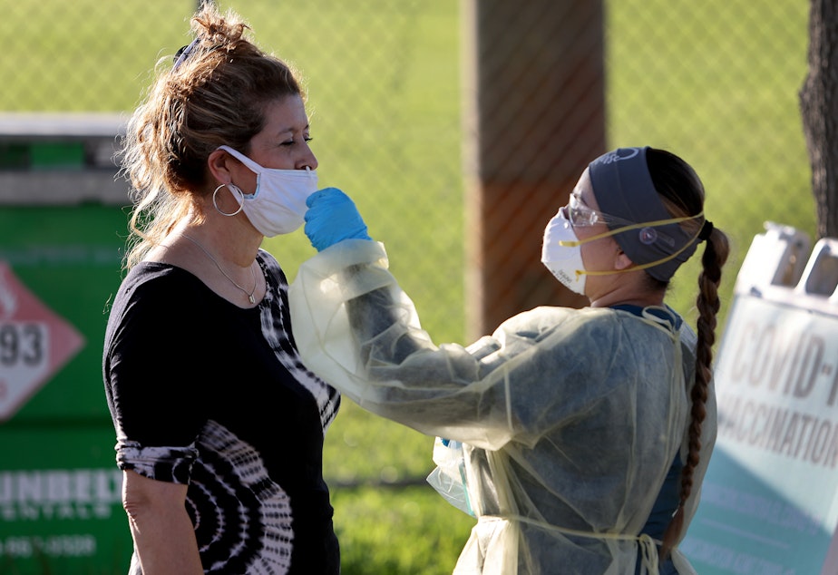 caption: Lylliette Ramirez gets a COVID-19 test done by a healthcare worker in January in North Miami, Florida.