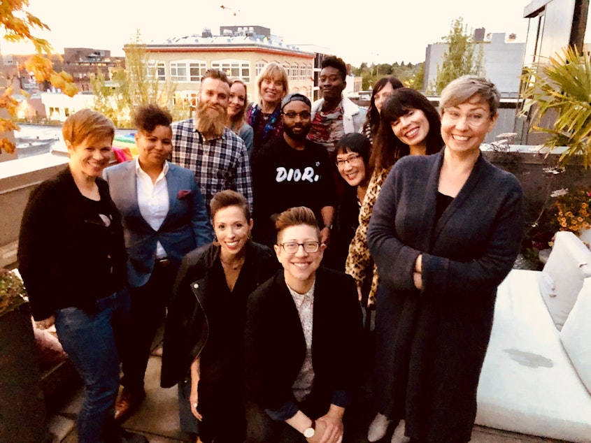 caption: Queeriosity Club 2019. From left to right, standing: Dacia Clay, Mellina White Cusack, Jeffrey Howard, KUOW reporter Ann Dornfeld, Jennifer Hegeman, Timothy Bardlavens, KUOW producer Adwoa Gyimah-Brempong, Christine Cox, Ginger Chien, Amanda Carter Gomes, KUOW producer Jeannie Yandel. Seated: KUOW producer Kristin Leong, Keri Zierler. The Cloud Room in Seattle. June 7, 2019.  