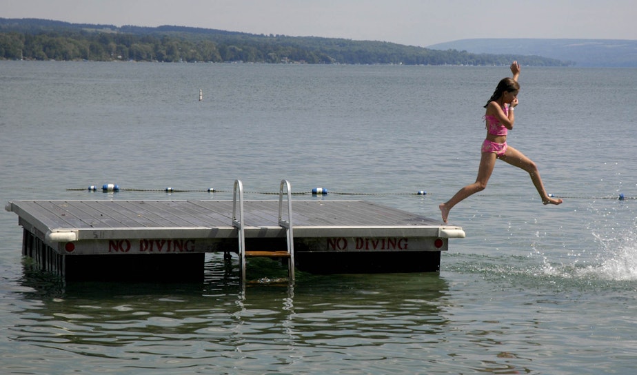 caption: A young swimmer jumps into Skaneateles Lake in Skaneateles, N.Y. The small lakeside town in upstate New York's Finger Lakes is just one of many destinations you could consider visiting this summer. (Kevin Rivoli/AP)