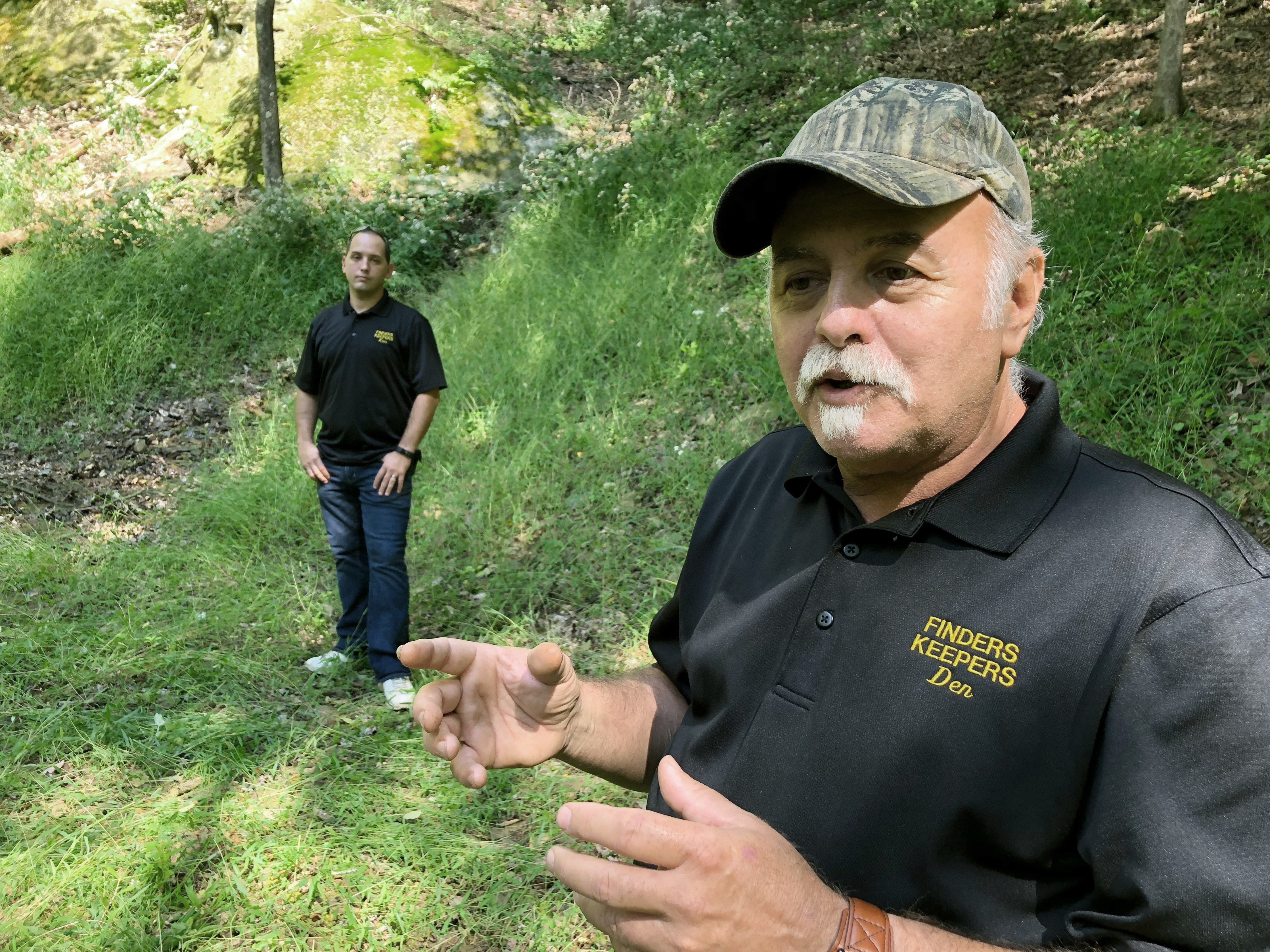 caption: Dennis Parada, right, and his son Kem Parada stand at the site of the FBI's dig for Civil War-era gold in September 2018 in Dents Run, Penn. A scientific report commissioned by the FBI shortly before agents went digging for buried treasure suggested that a huge quantity of gold was below the surface.