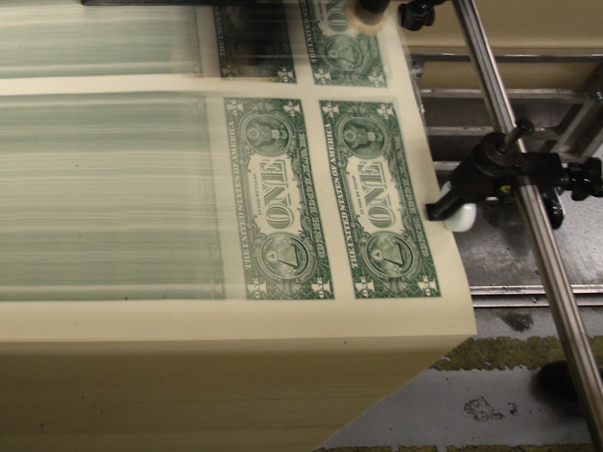 caption: Sheets of one-dollar bills run through the printing press at the Bureau of Engraving and Printing in 2015 in Washington, D.C. Congressional forecasters projected the federal deficit this fiscal year will hit its highest since World War II.
