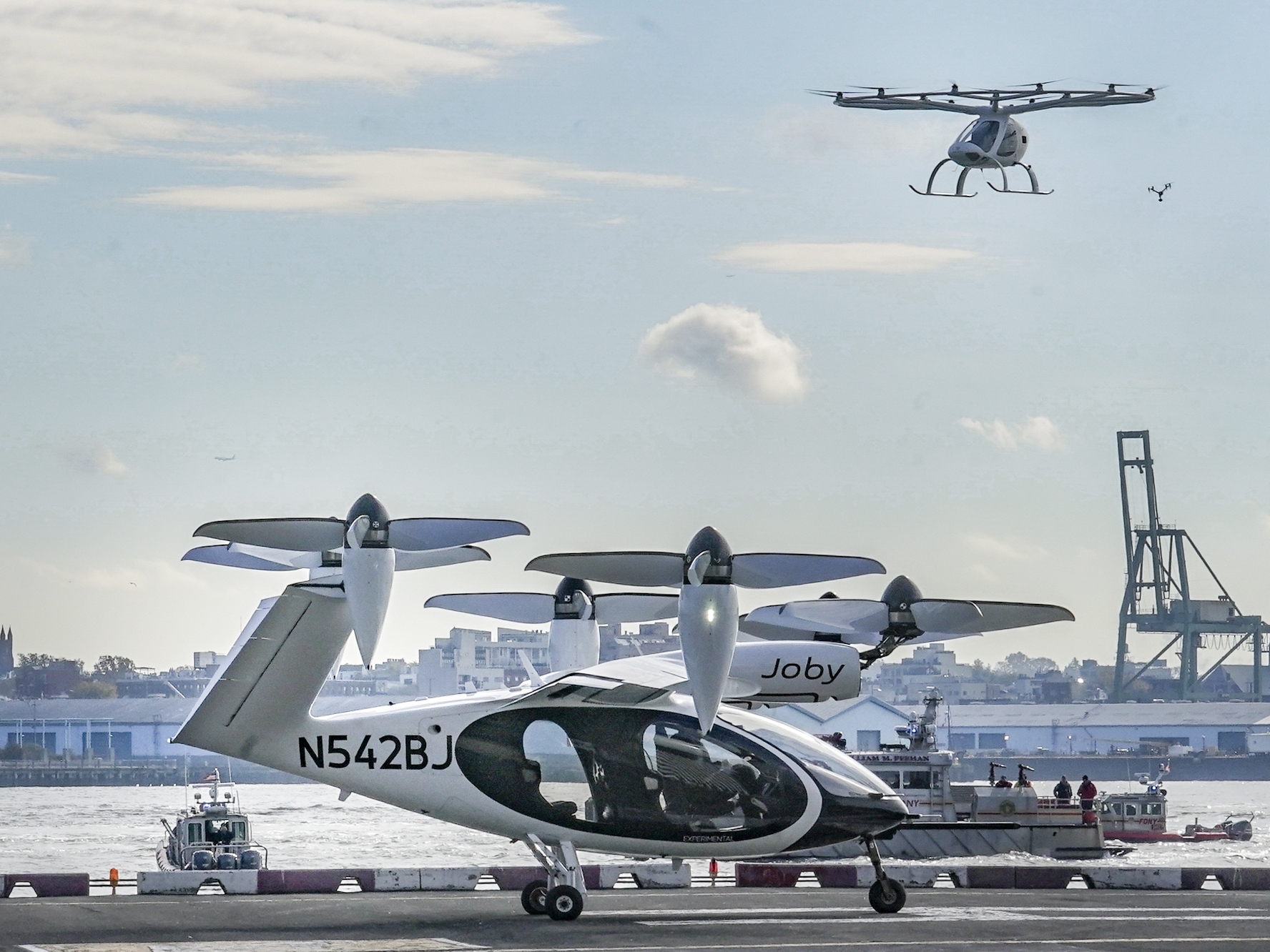 caption: An electric vertical takeoff and landing (eVTOL) aircraft, flies above the Joby eVTOL aircraft, during a demonstration of eVTOLs Nov. 13, 2023, in New York.