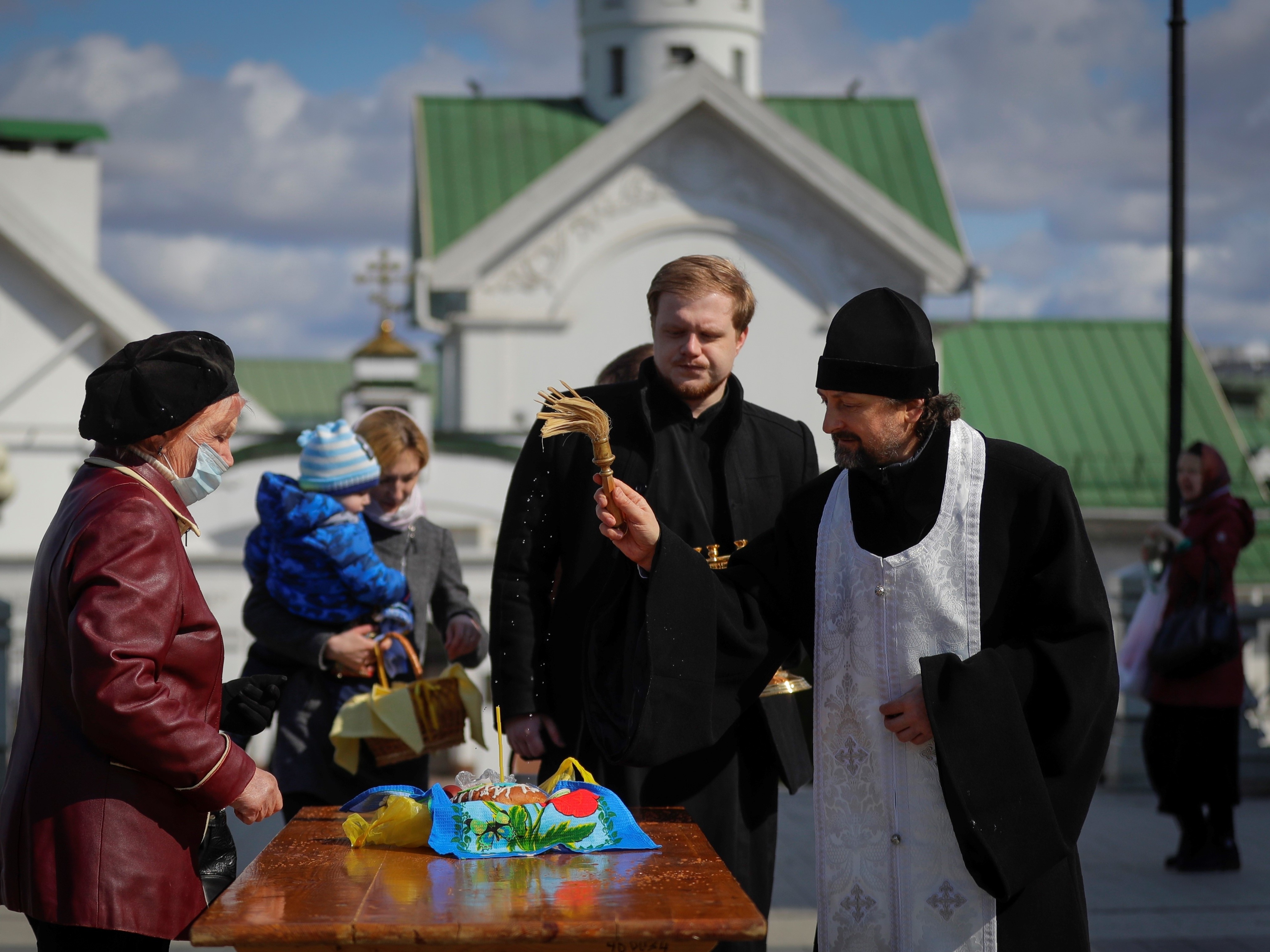 caption: An Orthodox priest blesses traditional Easter cakes and painted eggs in preparation for Easter, outside a church in Minsk, Belarus on Saturday.