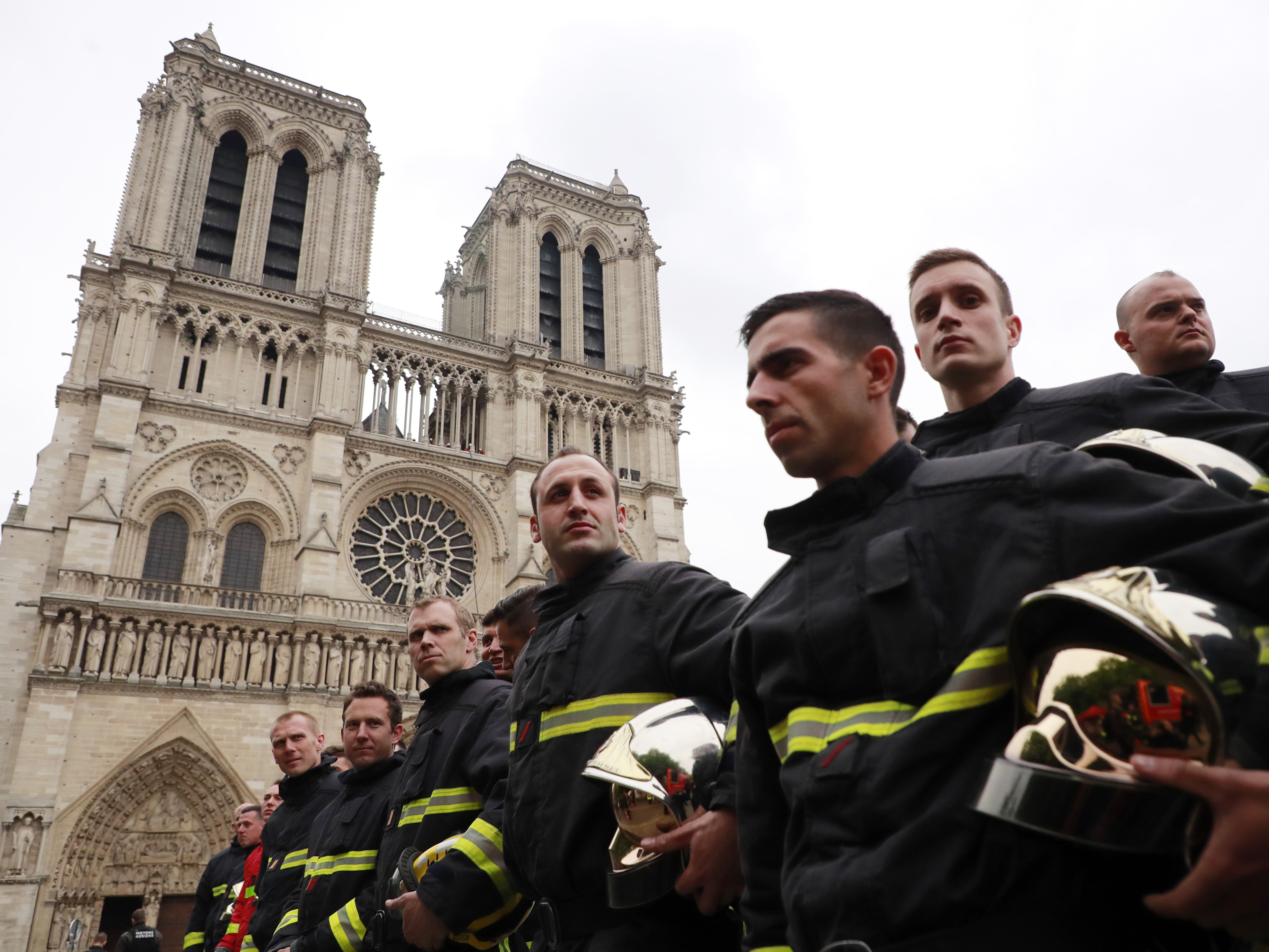 caption: Firefighters line up as they wait for French Interior Minister Christophe Castaner outside Notre Dame cathedral in Paris on Tuesday.