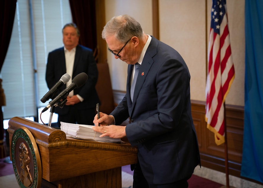 caption: Gov. Jay Inslee signs the supplemental operating budget into law. Before doing so, he vetoed more than $200 million in new spending in anticipation of the fiscal impacts of the COVID-19 pandemic.