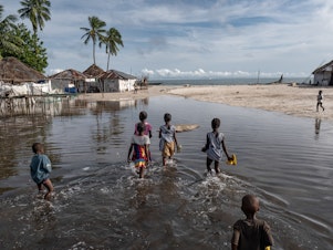 caption: Children wade through floodwater on Nyangai Island, Sierra Leone. Most of the island has already been lost to the sea, and what remains is routinely flooded at high tide.
