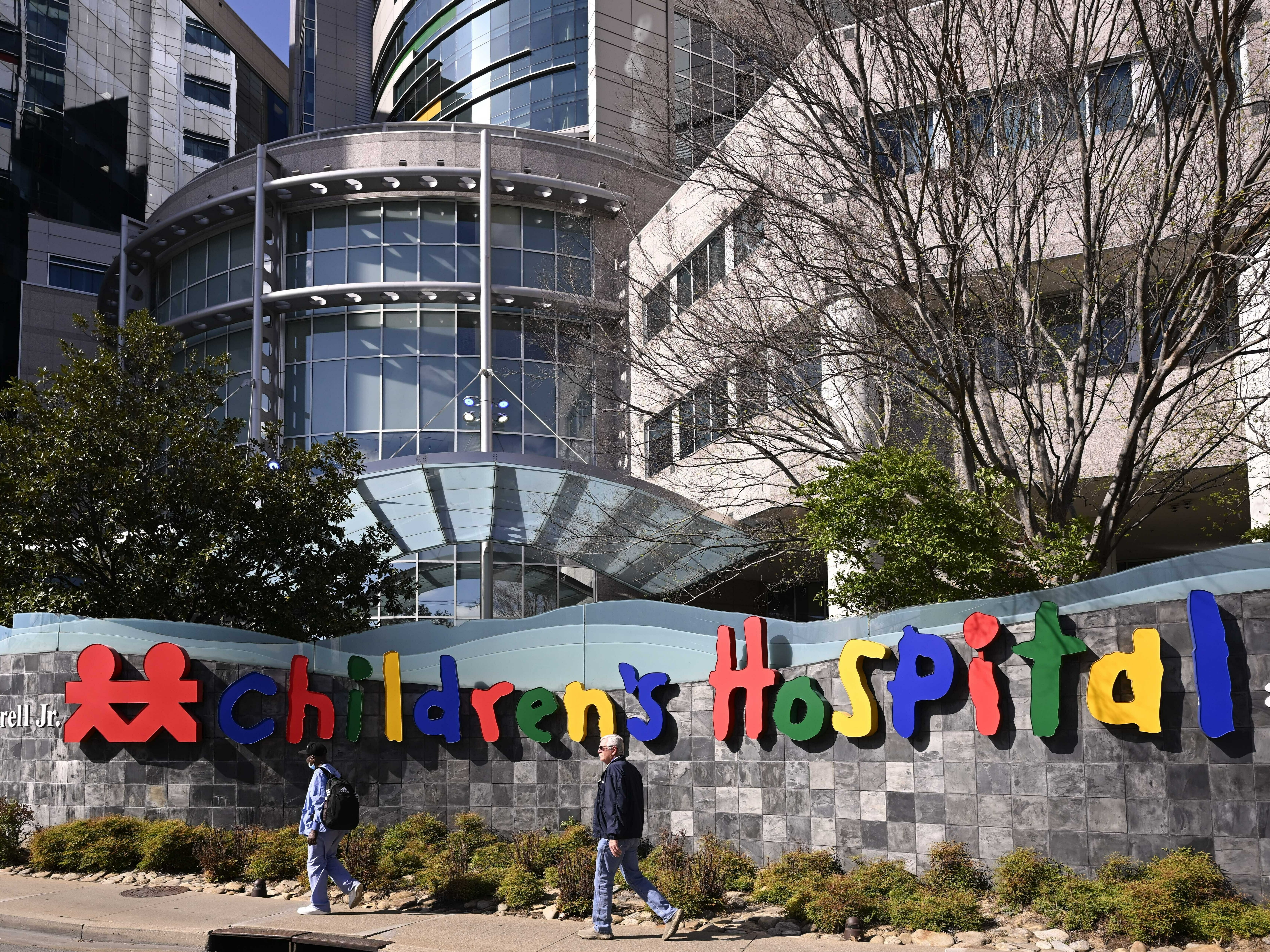 caption: People walk past the Monroe Carell Jr. Children's Hospital at Vanderbilt, in Nashville, Tenn., on Monday, where victims were taken after a shooting at the Covenant School.