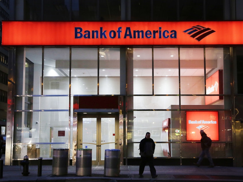caption: People walk past a branch of Bank of America in New York City in 2015. The bank announced Tuesday that it's raising its minimum wage to $20 an hour by 2021.