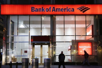 caption: People walk past a branch of Bank of America in New York City in 2015. The bank announced Tuesday that it's raising its minimum wage to $20 an hour by 2021.