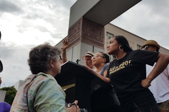 caption: Mara Willaford on the podium at a rally for presidential candidate Bernie Sanders in August. Willaford interrupted the event to call attention to the Black Lives Matter movement.