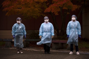 caption: From left, registered nurse Shu Kuang, registered nurse Tina Nguyen and patient services representative Denny Ho stand for a portrait following a shift of Covid-19 testing on Friday, November 20, 2020, at the International Community Health Services drive thru testing site on 8th Avenue South in Seattle's International District. 
