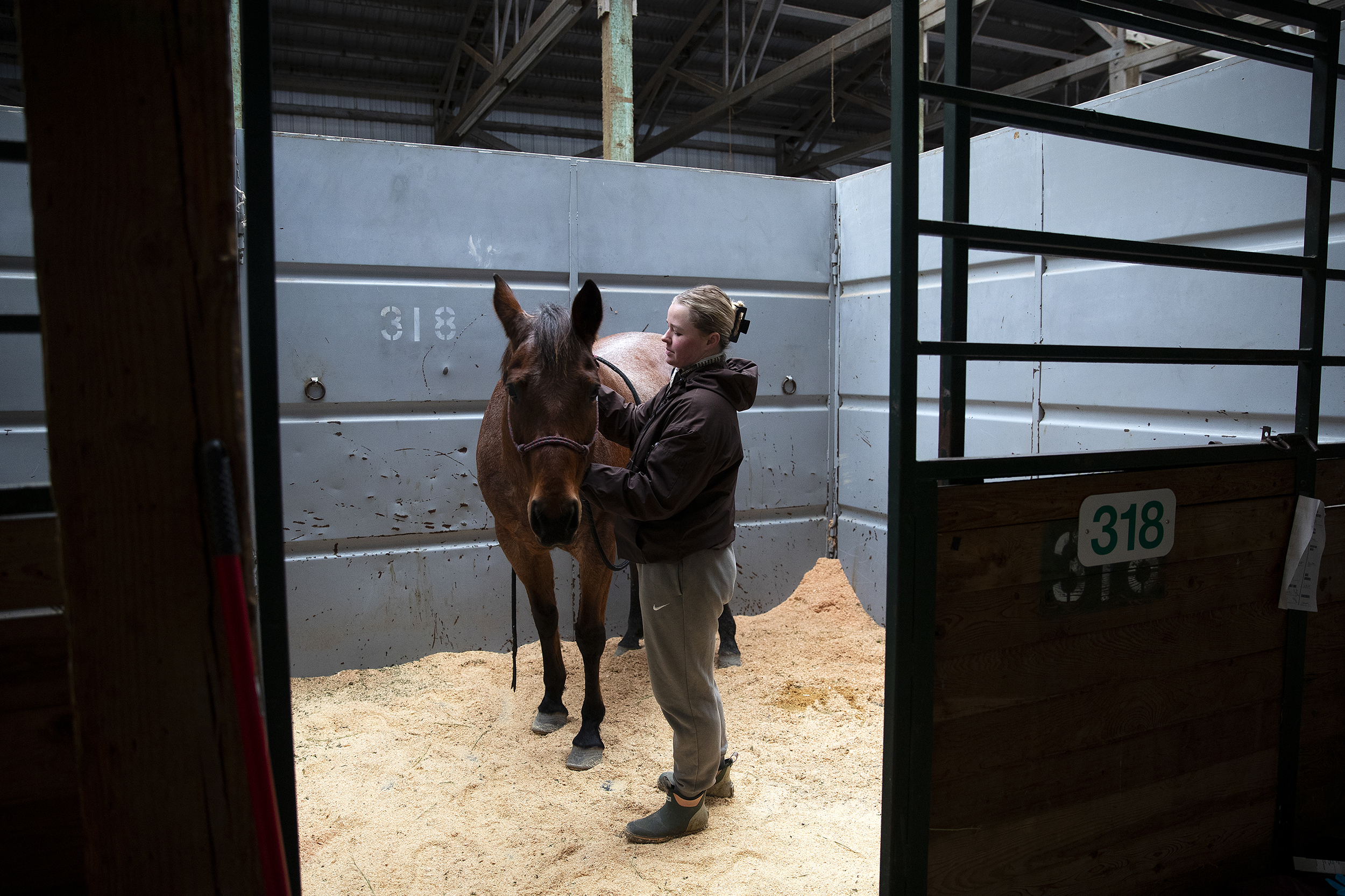 caption: Natascha Cooper, who evacuated from Snohomish with her horse, Willow, stands in a stall on Thursday, December 11, 2025, at the Evergreen State Fairgrounds in Monroe. 