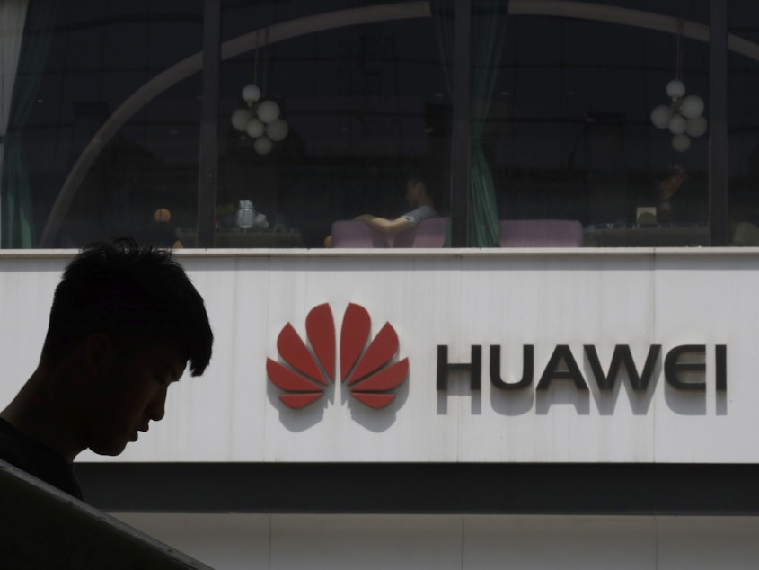 caption: A Chinese man is silhouetted near the Huawei logo in Beijing on Thursday. The Trump administration issued an executive order Wednesday apparently aimed at banning Huawei equipment from U.S. networks.