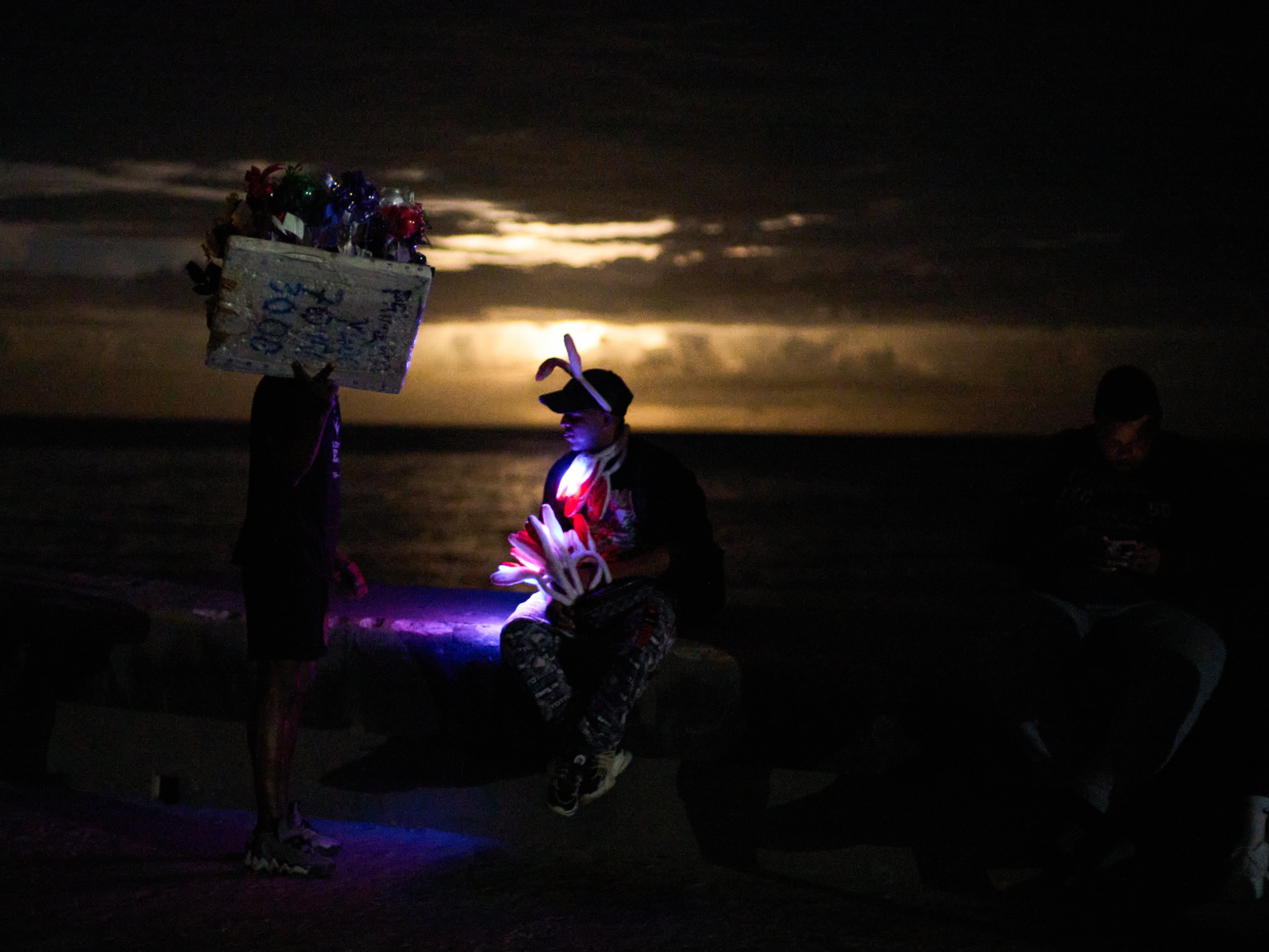 caption: Street vendors chat on the Malecón during a blackout in Havana, Monday, March 16, 2026.