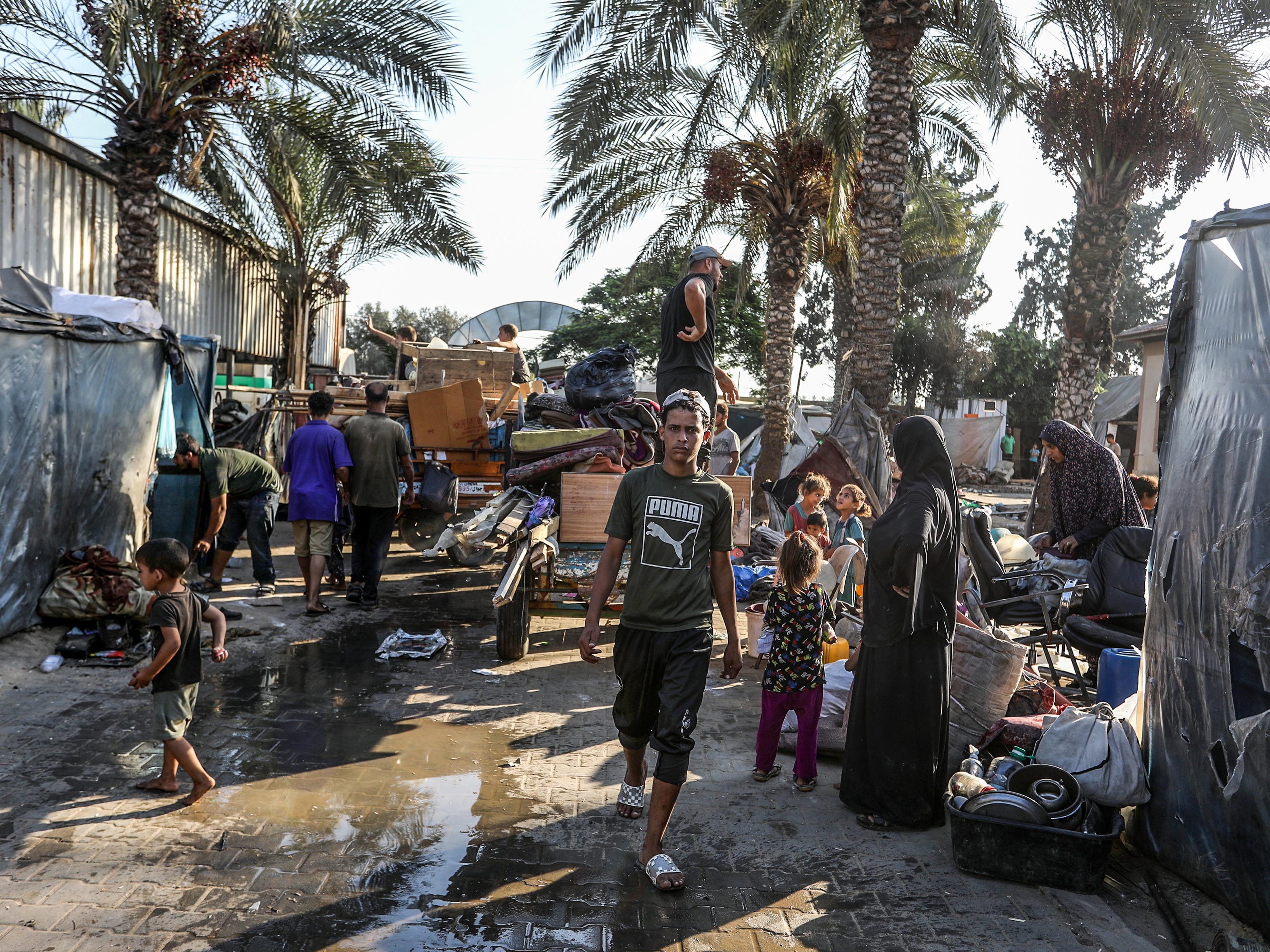 caption: Palestinians carry their belongings on their way to migrate for safer areas following the Israeli army's warning to evacuate the Dawa Faculty of the Ministry of Endowments in Deir al-Balah, Gaza, on Monday.