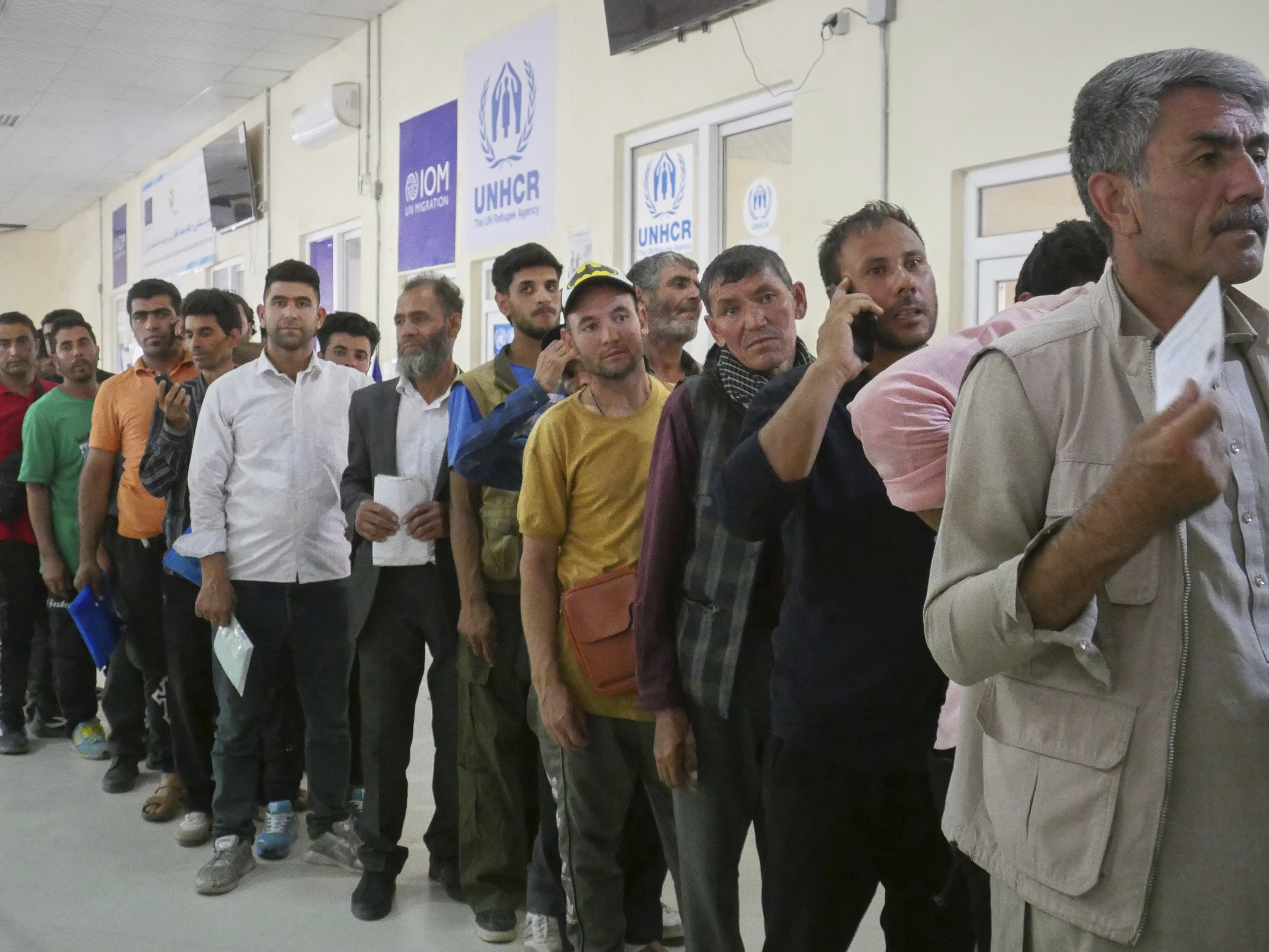 caption: Afghan refugees who returned after fleeing Iran to escape deportation and conflict line up at a UNHCR facility near the Islam Qala crossing in western Herat province, Afghanistan, on Friday, June 20, 2025.