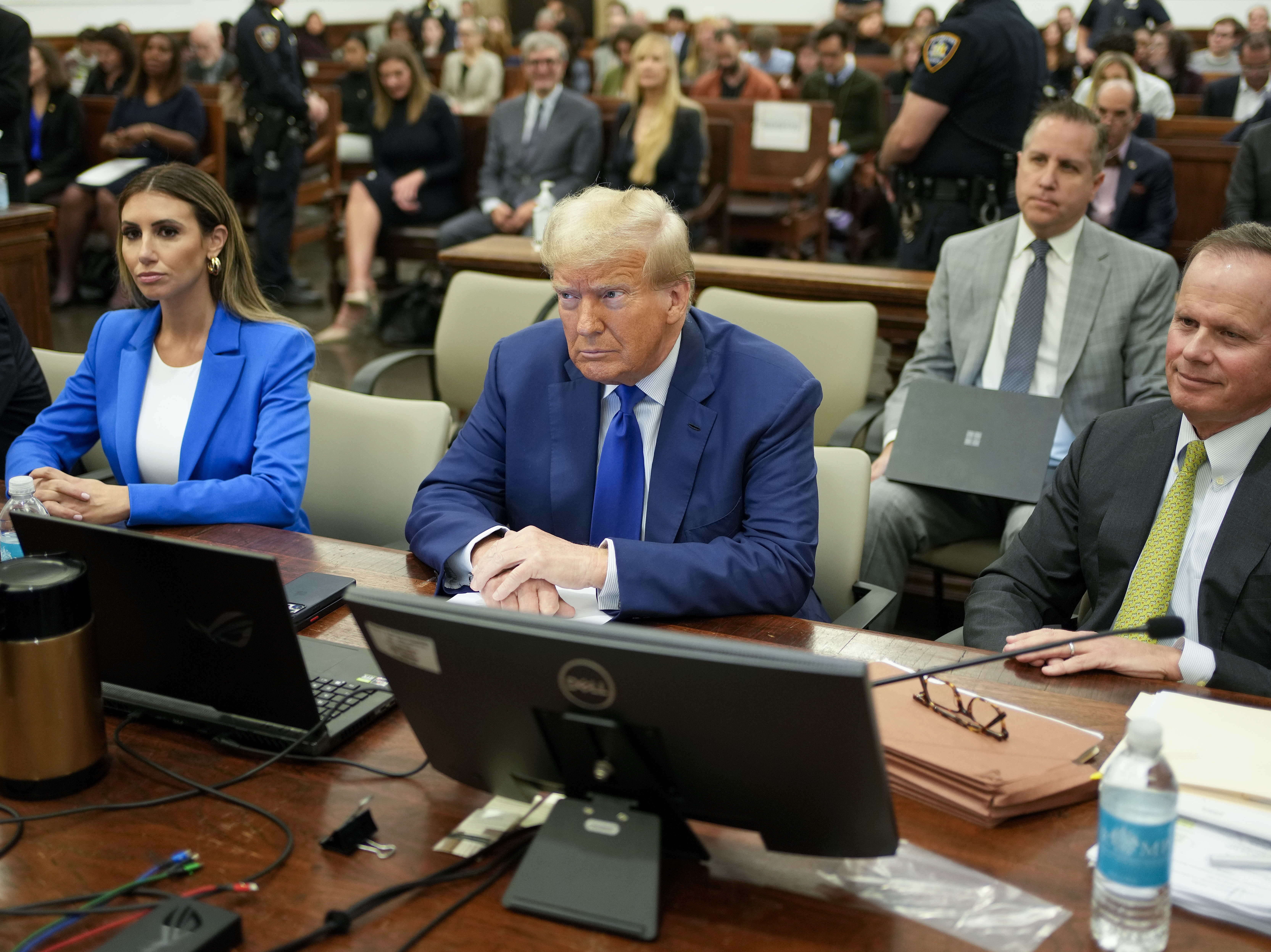 caption: Former President Donald Trump, center, flanked by his defense attorneys, Alina Habba, left, and Chris Kise, right.