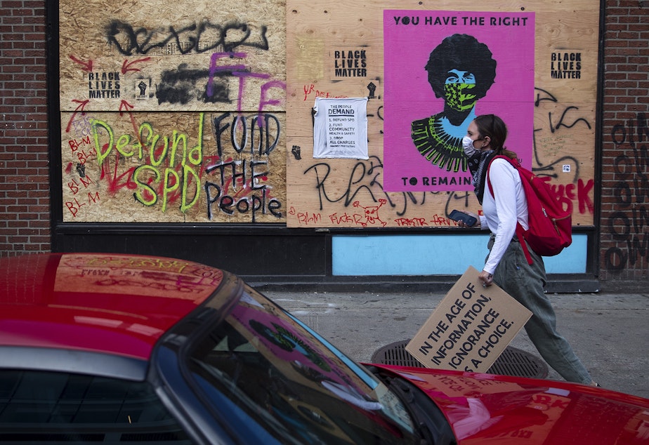 caption: A protester walks toward the intersection of 11th Avenue and East Pine Street on the 10th day of protests following the police killing of George Floyd on Sunday June 7, 2020, in Seattle.