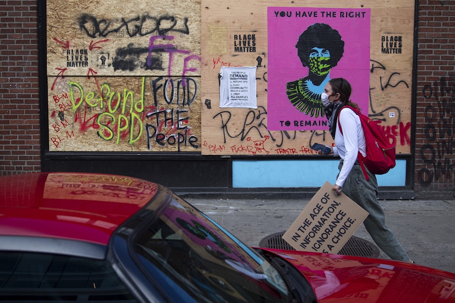 caption: A protester walks toward the intersection of 11th Avenue and East Pine Street on the 10th day of protests following the police killing of George Floyd on Sunday June 7, 2020, in Seattle.