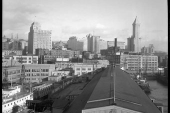caption: By the end of the 1920s, Seattle's waterfront was crowded with docks and its skyline was getting taller. This photo, taken from Colman Dock around 1931, is part of a panorama view of the city. The tallest landmarks are the Exchange Building (left) and Smith Tower (right).  