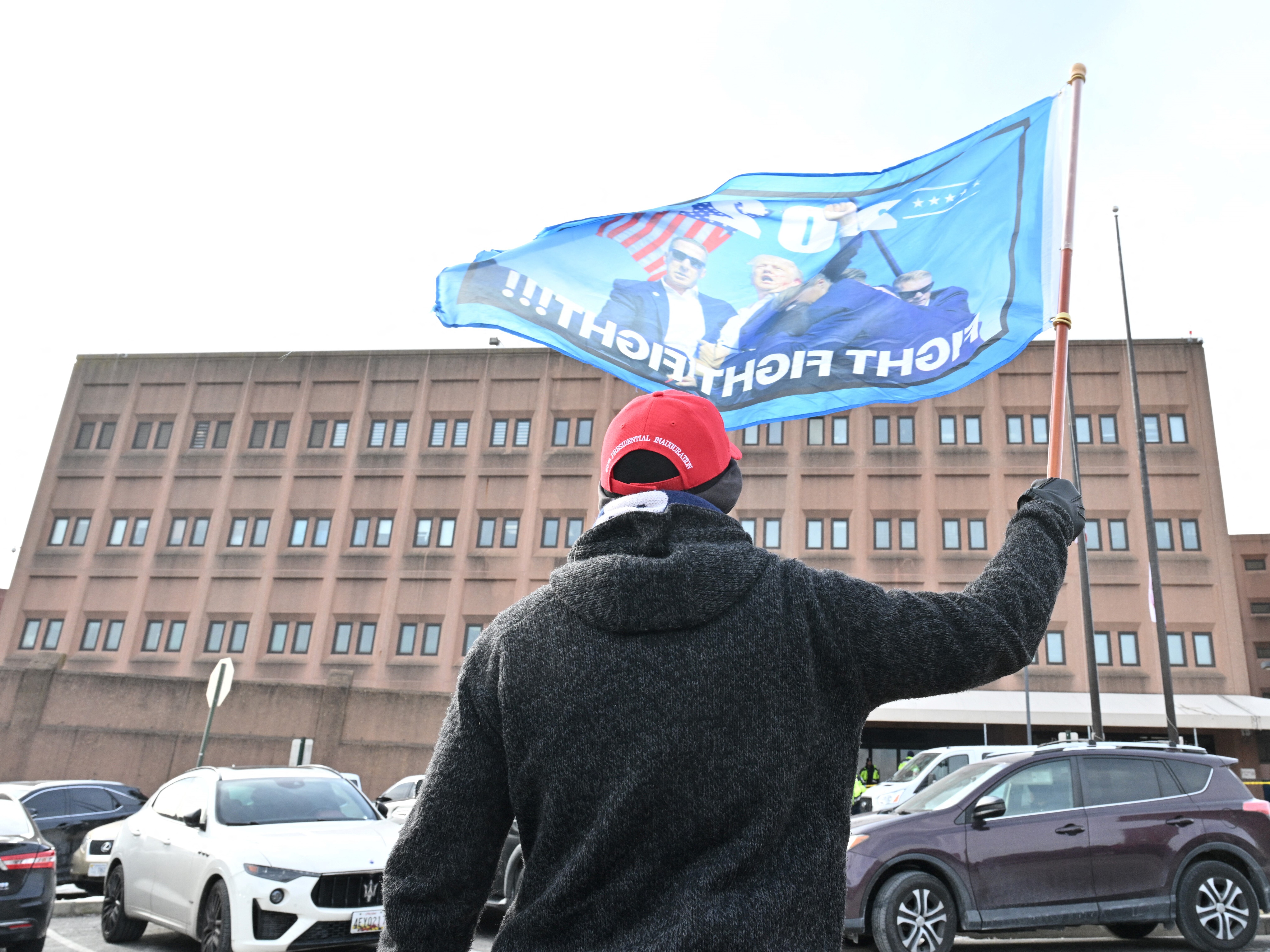 caption: A supporter of President Trump's waves a flag Tuesday outside a Washington, D.C., jail where some defendants from the Jan. 6 attack on the U.S. Capitol were being held. On Monday, Trump signed pardons for more than 1,500 people charged in the riot.
