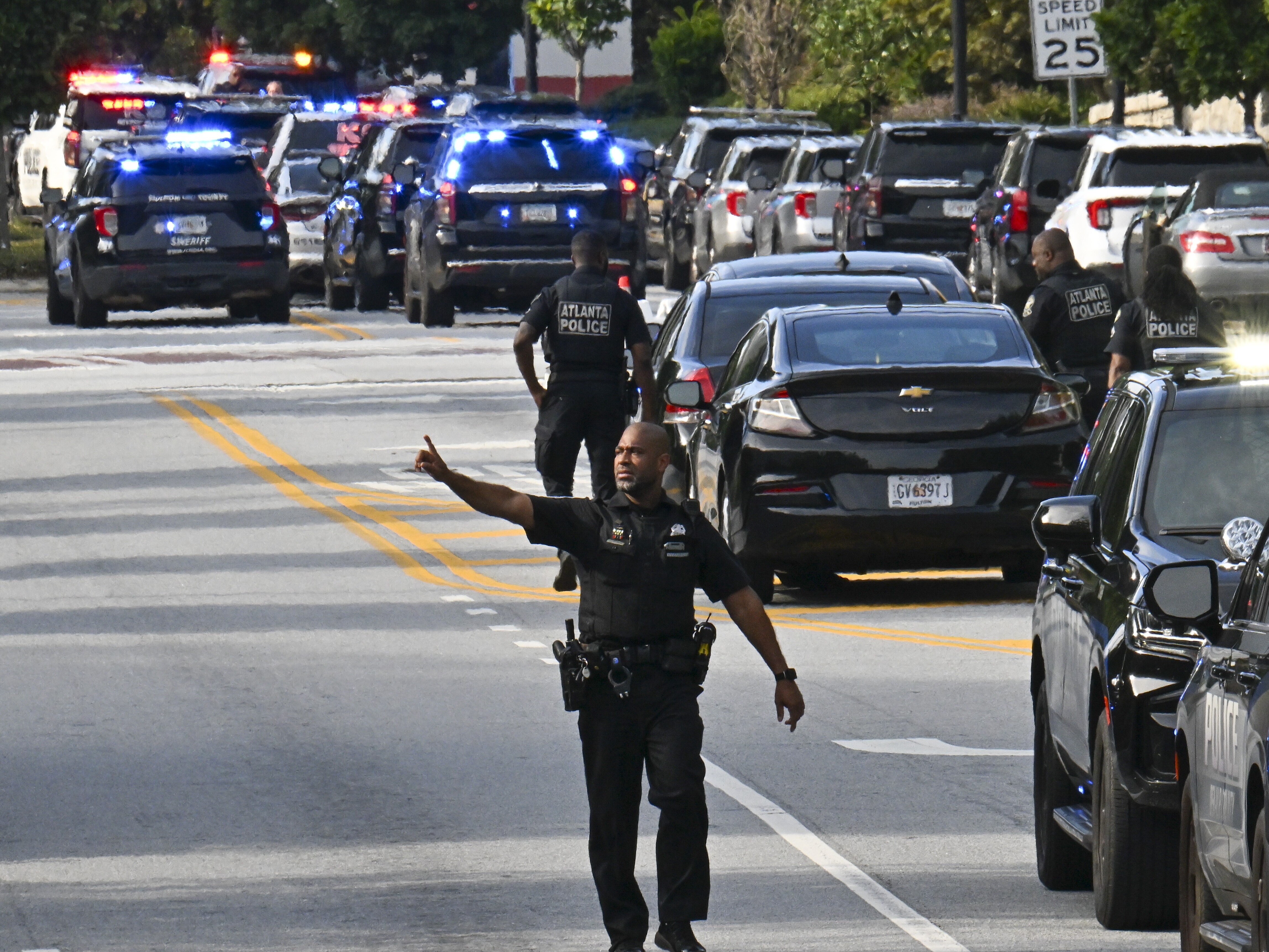 caption: Police officers block Clifton Road near Emory Hospital as they respond to a shooting near the campuses of the U.S. Centers for Disease Control and Prevention and Emory University on Friday.