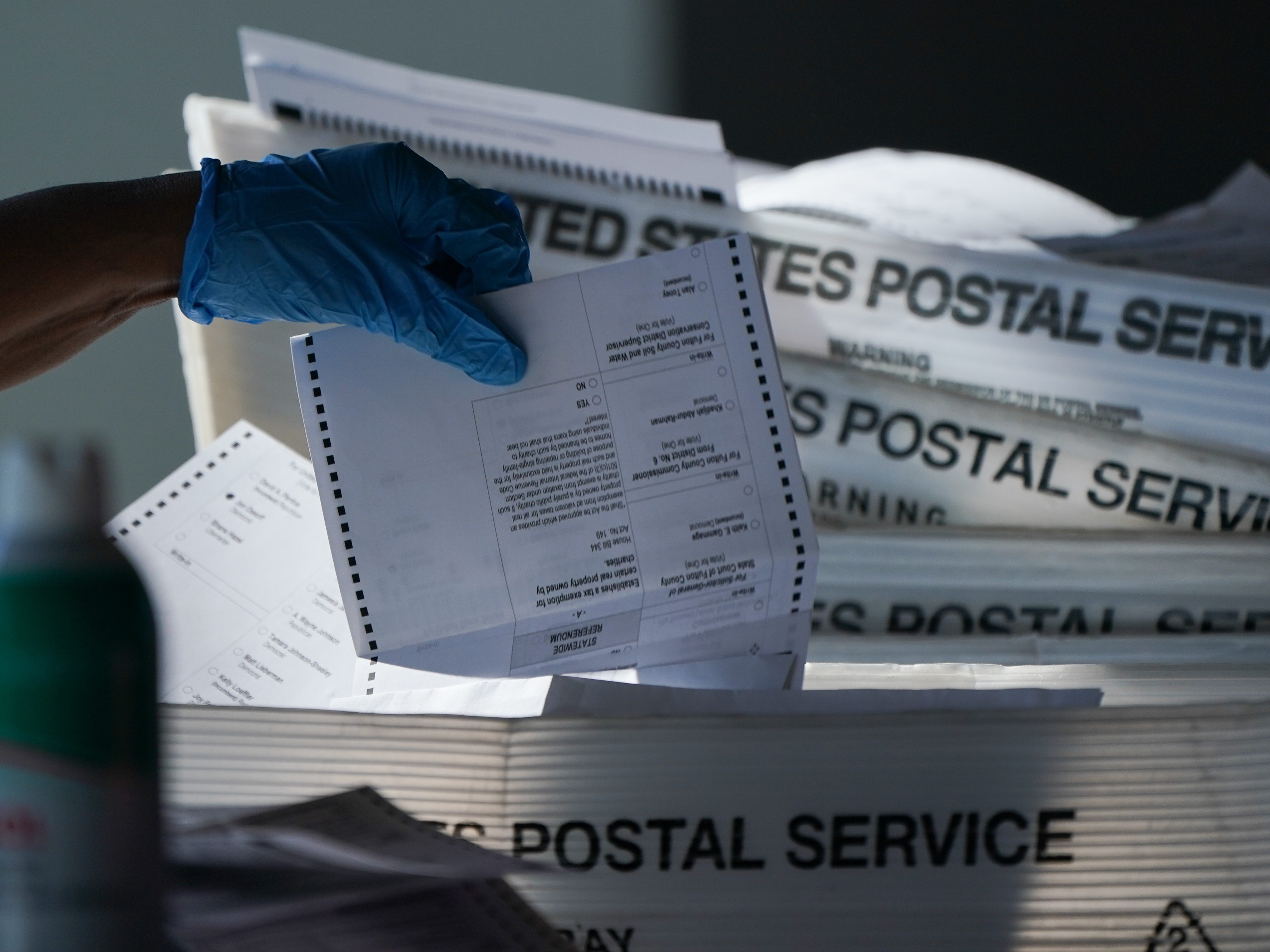caption: An election official counts absentee ballots for the 2020 election at State Farm Arena in Atlanta, on Wednesday.