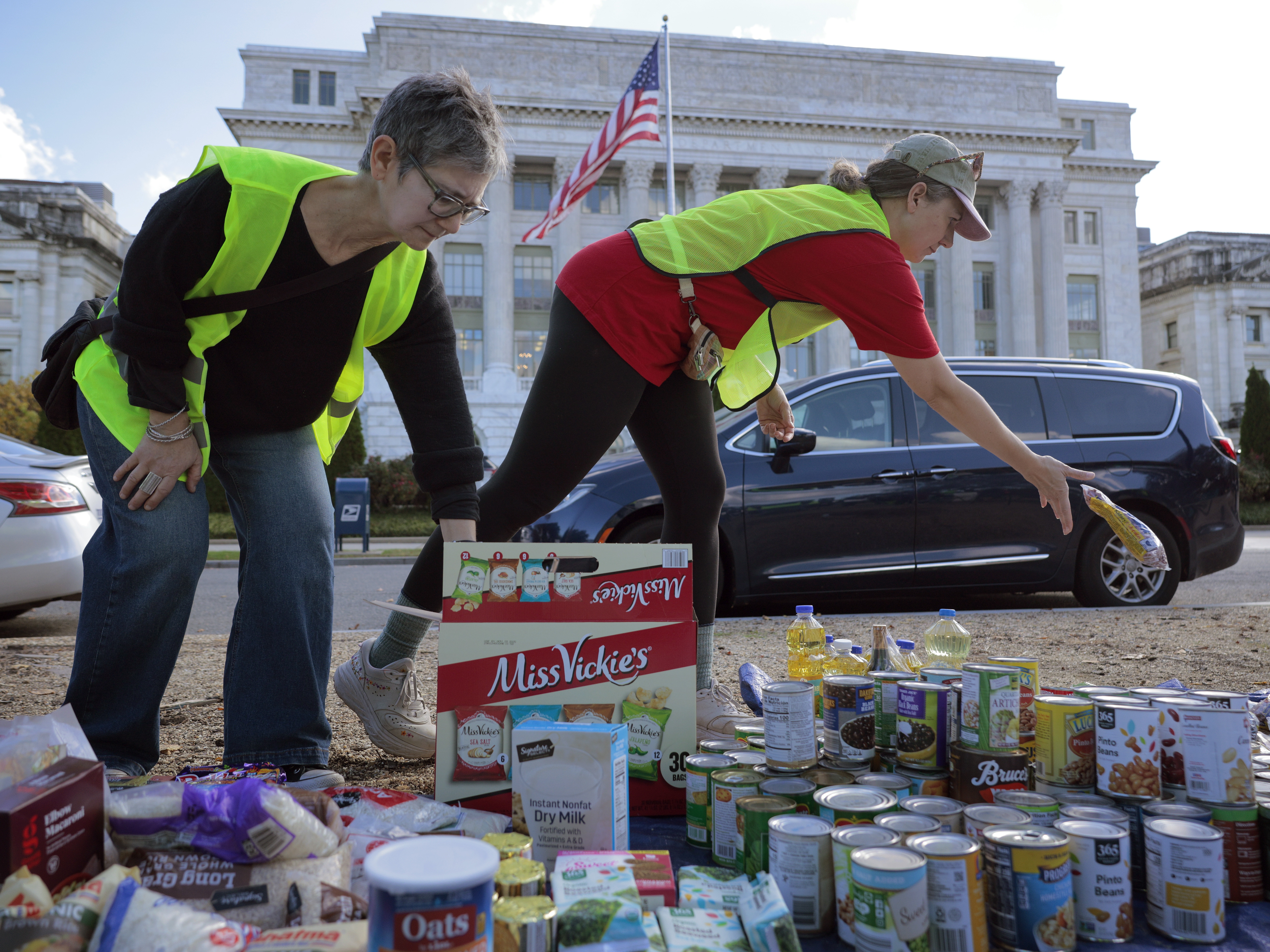 caption: Volunteers organize donated beans, powered milk and other nonperishable items during a food drive in front of the U.S. Department of Agriculture on Thursday in Washington, D.C. The event brought together faith leaders, food bank workers and furloughed federal employees who demanded that the Trump administration release billions in emergency funds for the Supplemental Nutrition Assistance Program.
