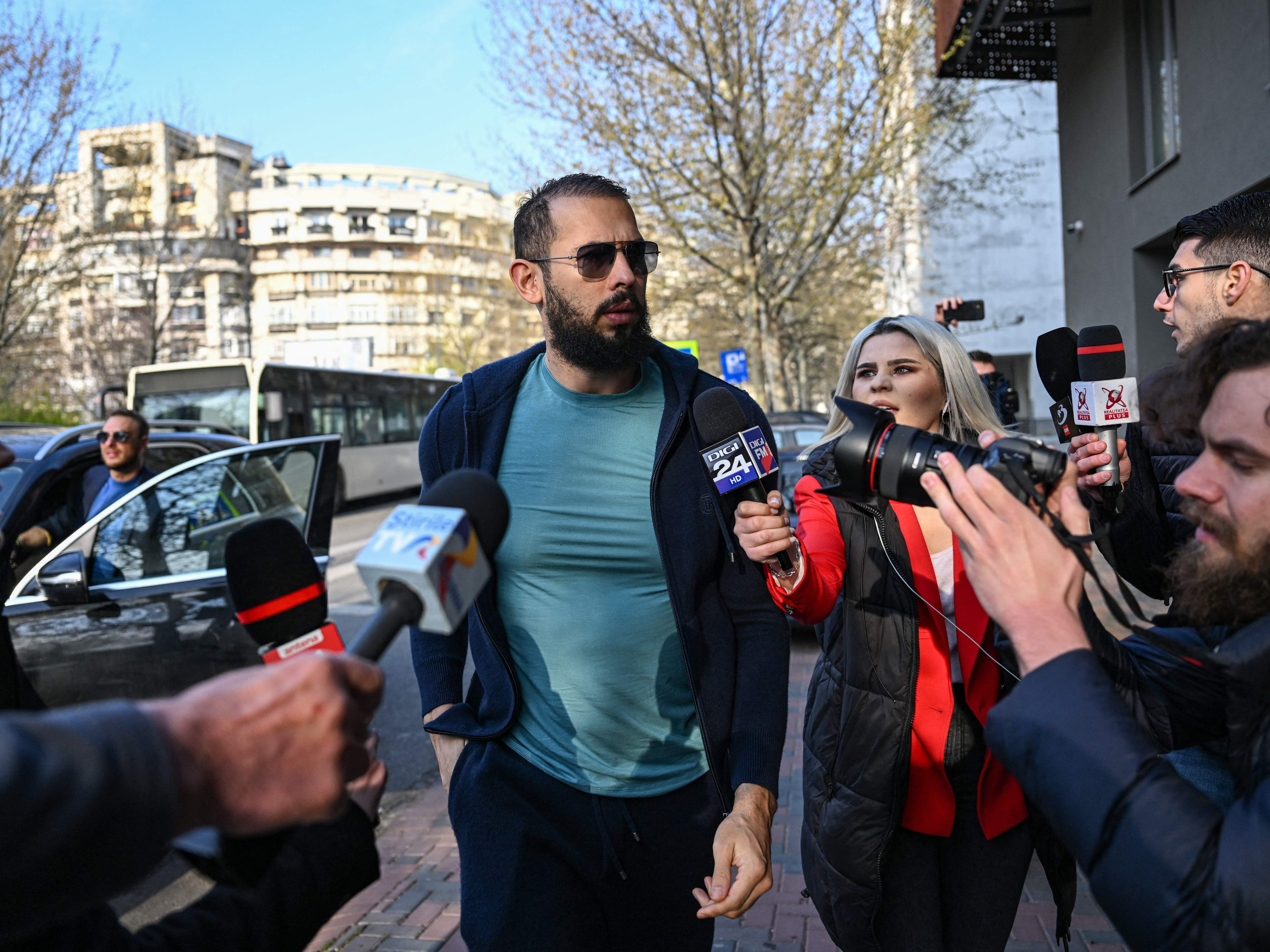 caption: Andrew Tate is now under a formal criminal indictment in Romania, months after his arrest. He's seen here in April,  arriving at the Directorate for the Investigation of Organized Crime and Terrorism (DIICOT).