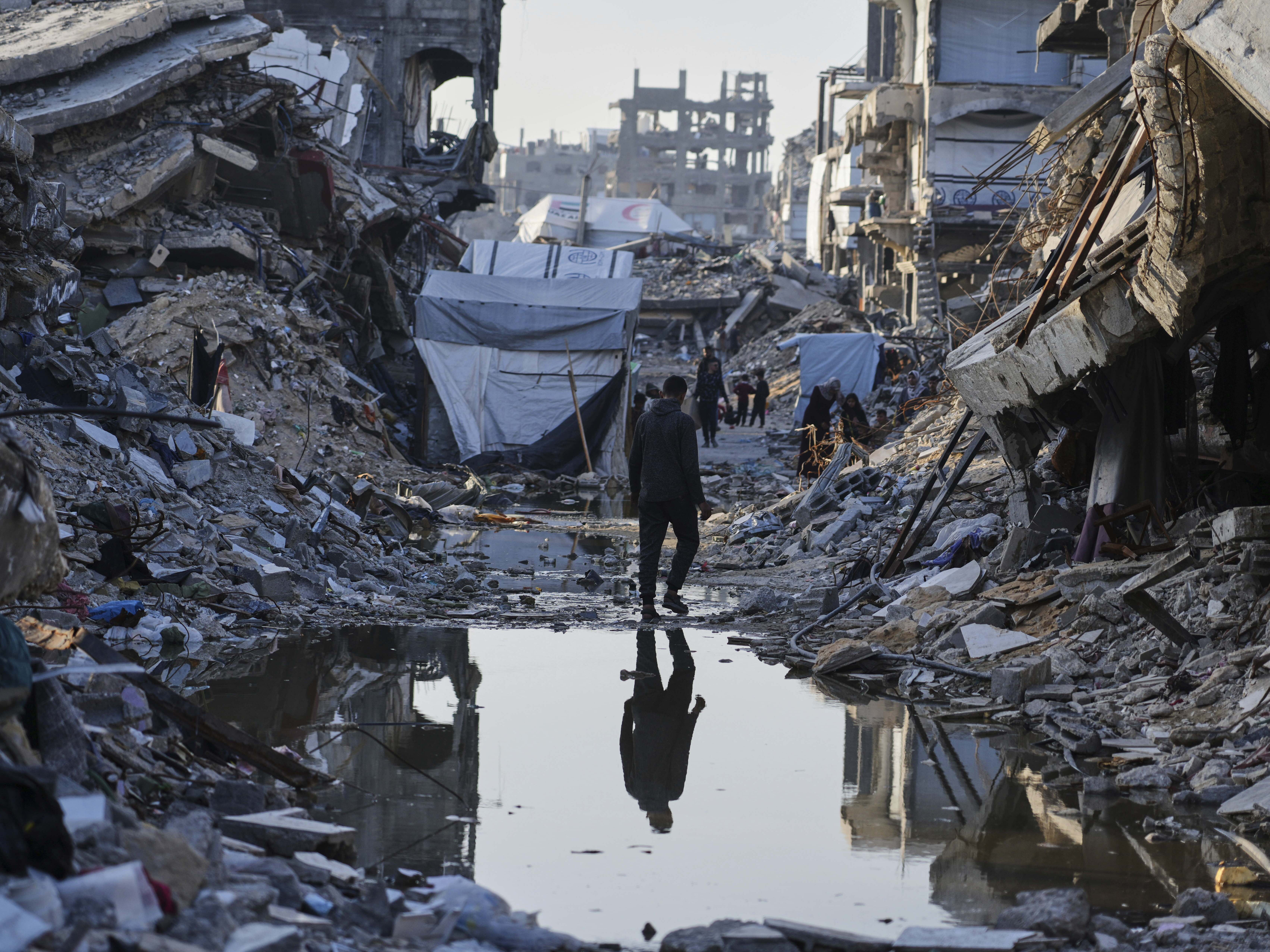 caption: Palestinians walk amid the rubble of destroyed homes and buildings in Jabaliya, northern Gaza Strip, March 14.