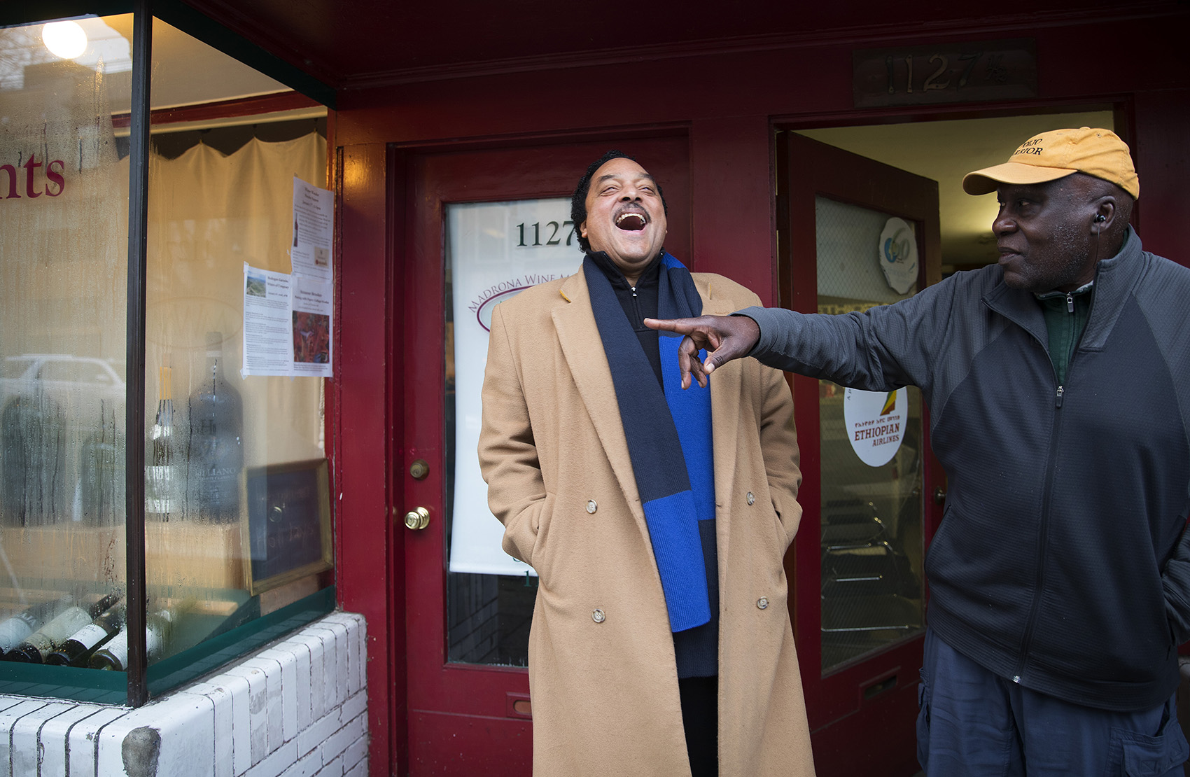 caption: Elmer Dixon, left, laughs with Ben Abe, right, the current owner of the space where the Seattle Black Panther Party had its first office on 34th Avenue in the Madrona neighborhood. Abe runs a travel business there now. Next door is a wine shop.