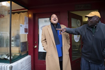 caption: Elmer Dixon, left, laughs with Ben Abe, right, the current owner of the space where the Seattle Black Panther Party had its first office on 34th Avenue in the Madrona neighborhood. Abe runs a travel business there now. Next door is a wine shop.