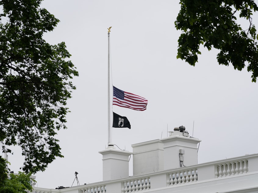 caption: The American flag flies at half-staff at the White House on Thursday as President Biden commemorates 1 million American lives lost due to COVID-19.