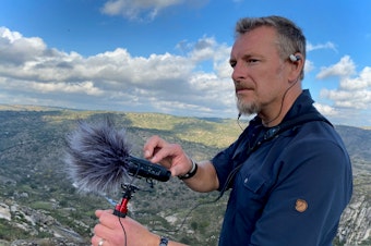 caption: Chris Morgan holds a microphone and records for THE WILD podcast in Portugal. Oct 2021. 