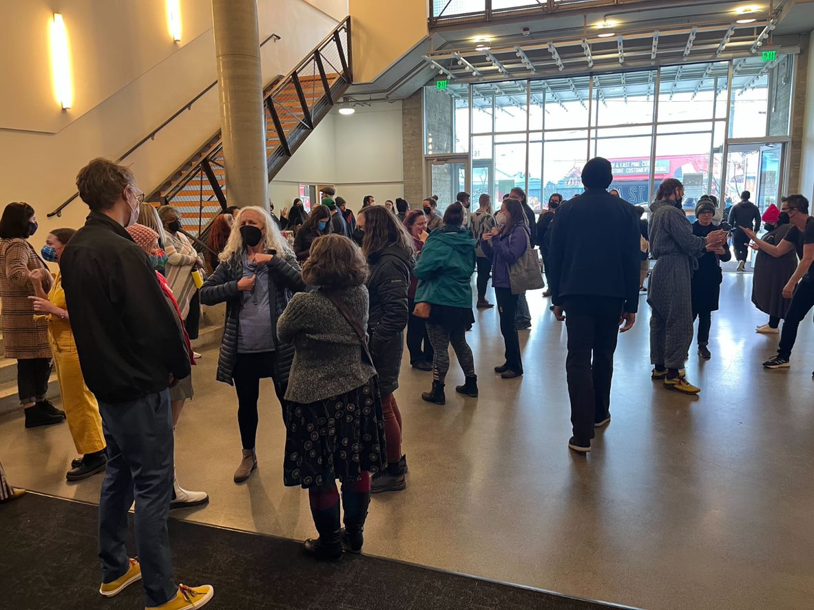caption: Audience members and actors gather in the lobby of 12th Avenue Arts after the final performance of Deaf Spotlight’s Short Play Festival on March 5, 2023.