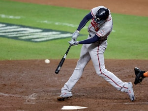 caption: Freddie Freeman of the Atlanta Braves hits a solo home run against the Houston Astros in Game Six of the World Series in November.