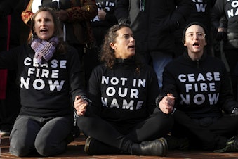 caption: Protesters lock hands during a Jewish Voice for Peace rally outside the Henry M. Jackson Federal Building while demanding that Sen. Patty Murray, D-Wash., call for a ceasefire in the Israel-Hamas war Friday, Nov. 3, 2023, in Seattle.