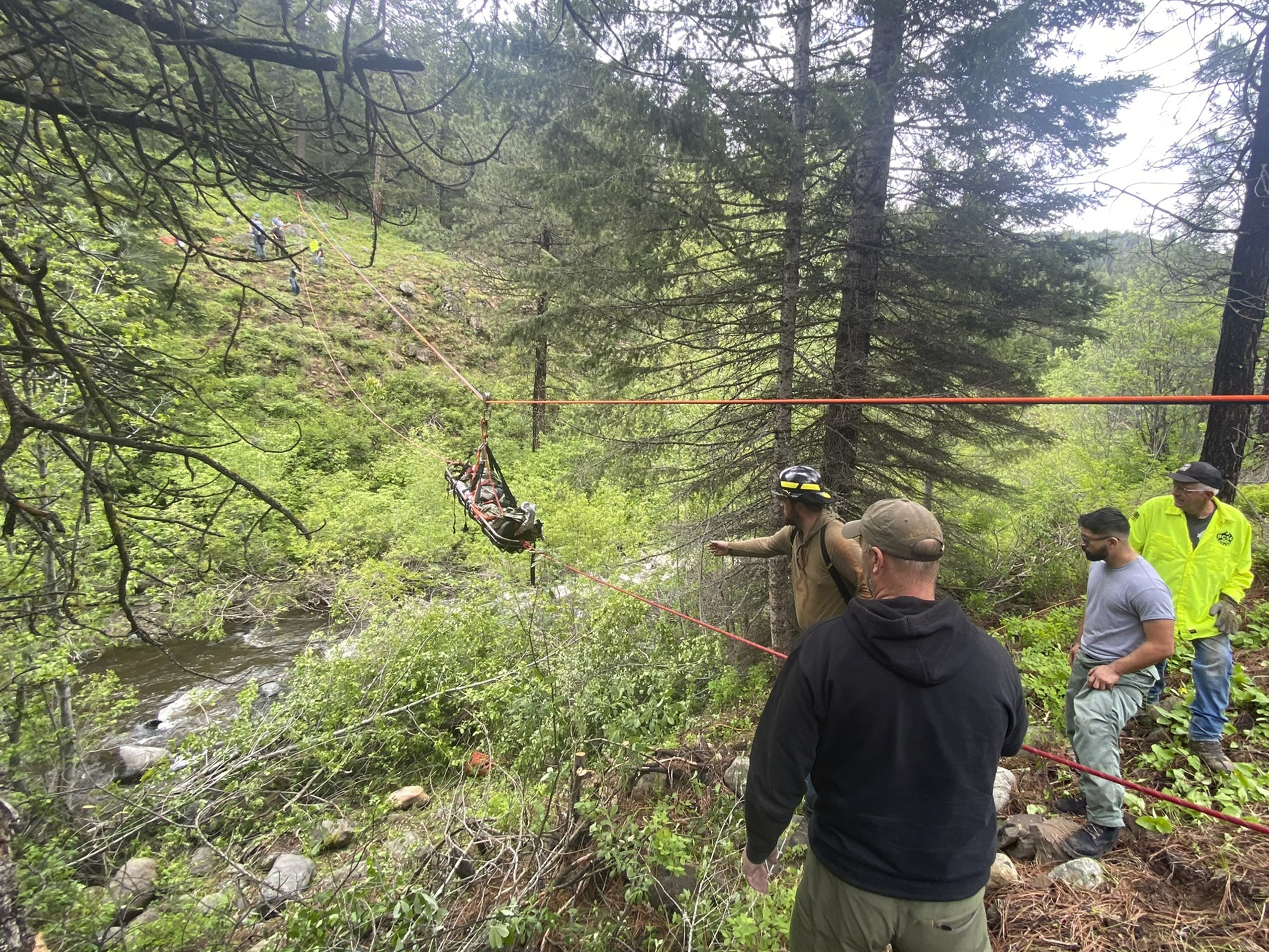caption: In this image provided by the Baker County Sheriff's Office, responders aid in rescue efforts after a vehicle went into an embankment on U.S. Forest Service Road 39 on June 3, 2024, in Oregon. A dog helped his owner get rescued after the crash by traveling nearly four miles to the campsite where the man was staying with family, which alerted them that something was wrong, authorities said.  