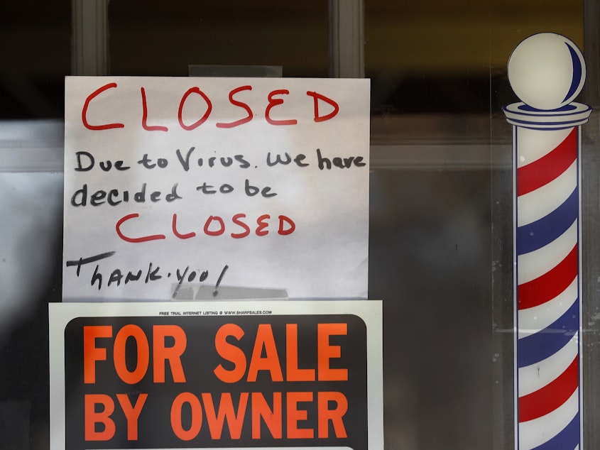 caption: "For Sale By Owner" and "Closed Due to Virus" signs are displayed in the window of Images On Mack in Grosse Pointe Woods, Mich. Congress is considering ways to help those struggling during the economic downturn and stabilize businesses hoping to reopen.