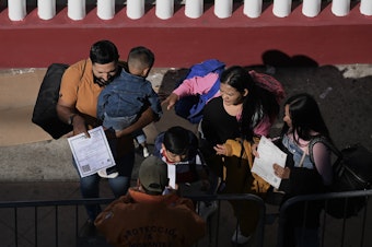 caption: A migrant family shows their paperwork to Mexican immigration officials to proceed with their CBP One asylum appointments at the Chaparral pedestrian border in Tijuana, Mexico to cross to the U.S. on Thursday.