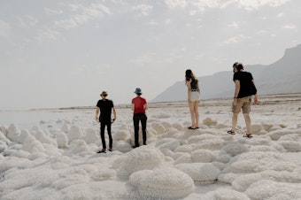 caption: Visitors, including Dead Sea researcher Yael Kiro from Israel's Weizmann Institute of Science (second from left), examine salt formations on the shore of the Dead Sea in Israel on Nov. 5.